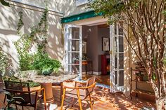 an outdoor patio with chairs, table and potted plants