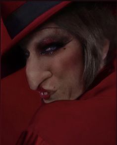 a woman with dark makeup wearing a red hat