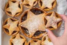 a hand holding a star shaped pastry with powdered sugar on top