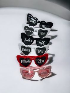 heart shaped sunglasses with names on them and hearts in the shape of glasses are sitting next to each other