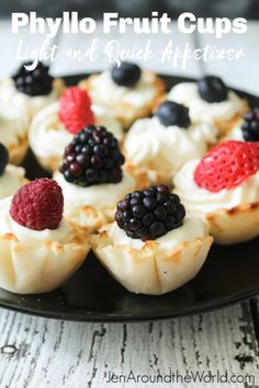 some fruit cups are sitting on a black plate with berries and cream toppings in them