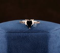 a black diamond ring sitting on top of a blue cloth covered hat with the word love written in it