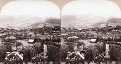 an old time photo of people on horses in the mountains with houses and buildings behind them