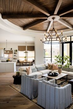 a living room filled with lots of furniture and a chandelier hanging from the ceiling