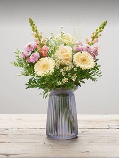 a vase filled with lots of flowers on top of a wooden table