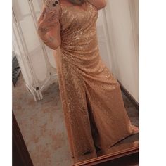 a woman taking a selfie in front of a mirror wearing a gold dress and holding a teddy bear