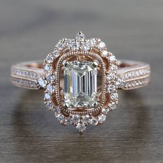 a fancy engagement ring with an emerald center surrounded by white and rose gold pave