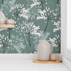 a teal and white floral wallpaper in a kitchen with two vases on the counter