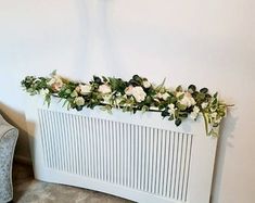 a white radiator sitting next to a chair in a room with flowers on the radiator