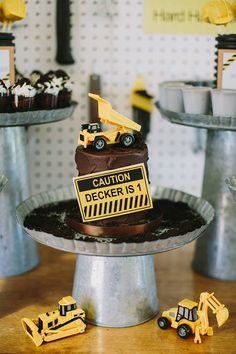 a table topped with cakes covered in chocolate frosting and construction themed icing on top of metal pans