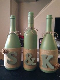 three green wine bottles with the letters s and k on them are sitting on a table