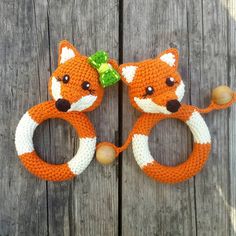 two crocheted foxes are sitting next to each other on a wooden surface, one is orange and the other is white