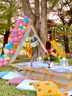 an outdoor party with balloons and decorations on the ground, including a teepee tent