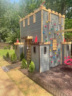 a play house with climbing wall and swing set