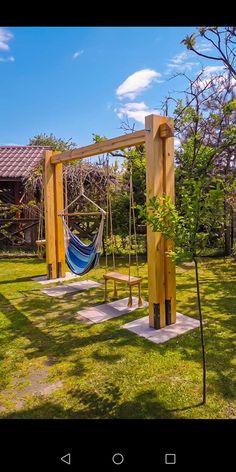 a wooden swing set with a hammock hanging from it's sides in the grass