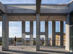 a man is standing in the middle of an open area with concrete pillars and windows