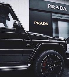 a black jeep parked in front of a prada store