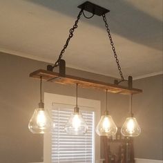 three light fixtures hanging from a wooden beam in a dining room with gray walls and white trim