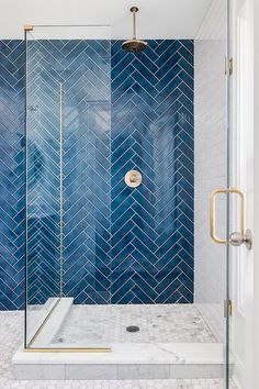 a bathroom with blue tile and gold accents on the shower wall, along with a walk in shower