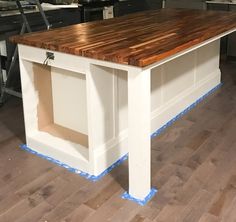 a kitchen island with blue tape on the bottom and drawers under it, in a room with hardwood flooring