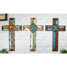 three wooden crosses on a white brick wall