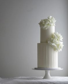 a three tiered cake with white flowers on top