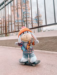 a stuffed animal is riding on a skateboard in front of a castle like building