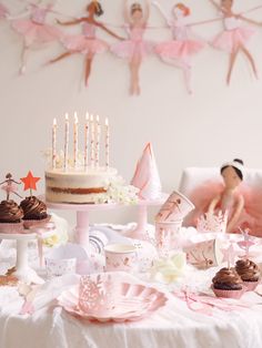 a table topped with cake and cupcakes on top of a white table cloth