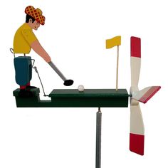 a man hitting a golf ball on top of a green table next to a red and white flag