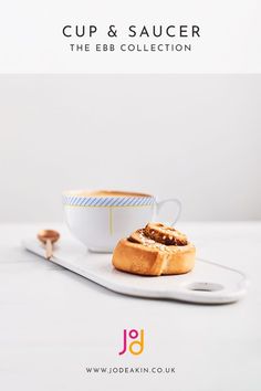 a cup and saucer sitting on top of a white plate next to a spoon