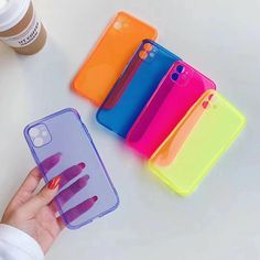 a hand holding a phone case next to five different colored cases on a white surface