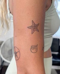 a woman's arm with starfish, sand dollar and shell tattoos on it