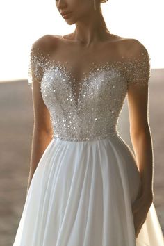 a woman in a white wedding dress with sequins on her shoulders and shoulder