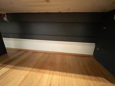 an empty room with black walls and wood floors