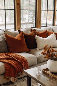 a living room filled with lots of furniture next to two large windows and a coffee table