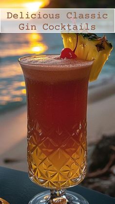 a glass filled with a drink sitting on top of a table next to the ocean