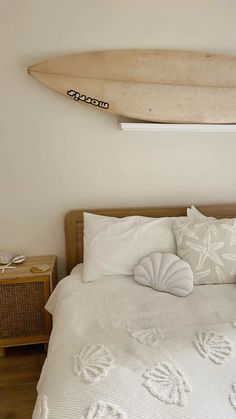 a surfboard mounted to the wall above a bed with pillows and blankets on it