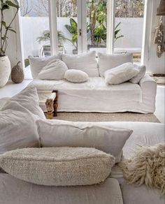 a living room filled with white furniture and lots of pillows on top of it's couches