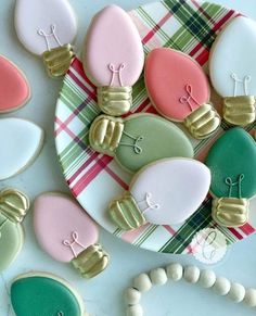 decorated cookies are arranged on a plate next to a bead bracelet and necklaces