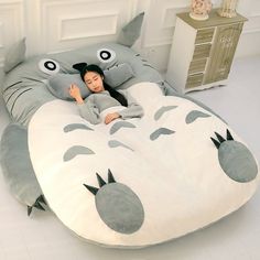 a woman laying in a bed shaped like a totoro