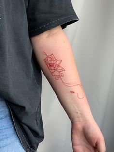 a person with a red ink tattoo on their arm holding onto a white object in his hand