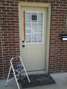 a stepladder stands in front of a door with an orange ribbon on it