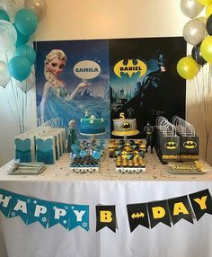 a table topped with cake and balloons next to a batman poster on top of a white table cloth