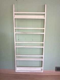 a white shelf sitting on top of a hard wood floor next to a green wall