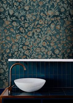 a bowl sink sitting on top of a counter in front of a wallpapered wall