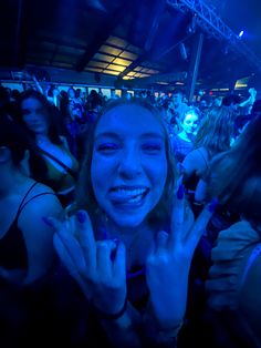 a woman is smiling and holding her hands up in the air at a music festival