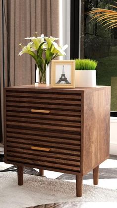 a wooden dresser sitting in front of a window next to a vase filled with flowers