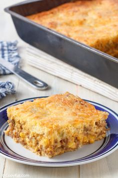 a piece of casserole on a plate next to a baking pan and fork