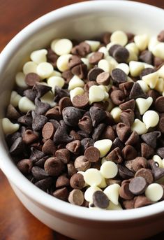 a white bowl filled with chocolate chips and marshmallows on top of a wooden table