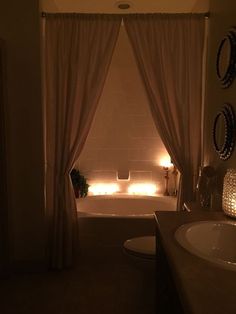 a bath room with a tub a sink and some lights on the wall next to it